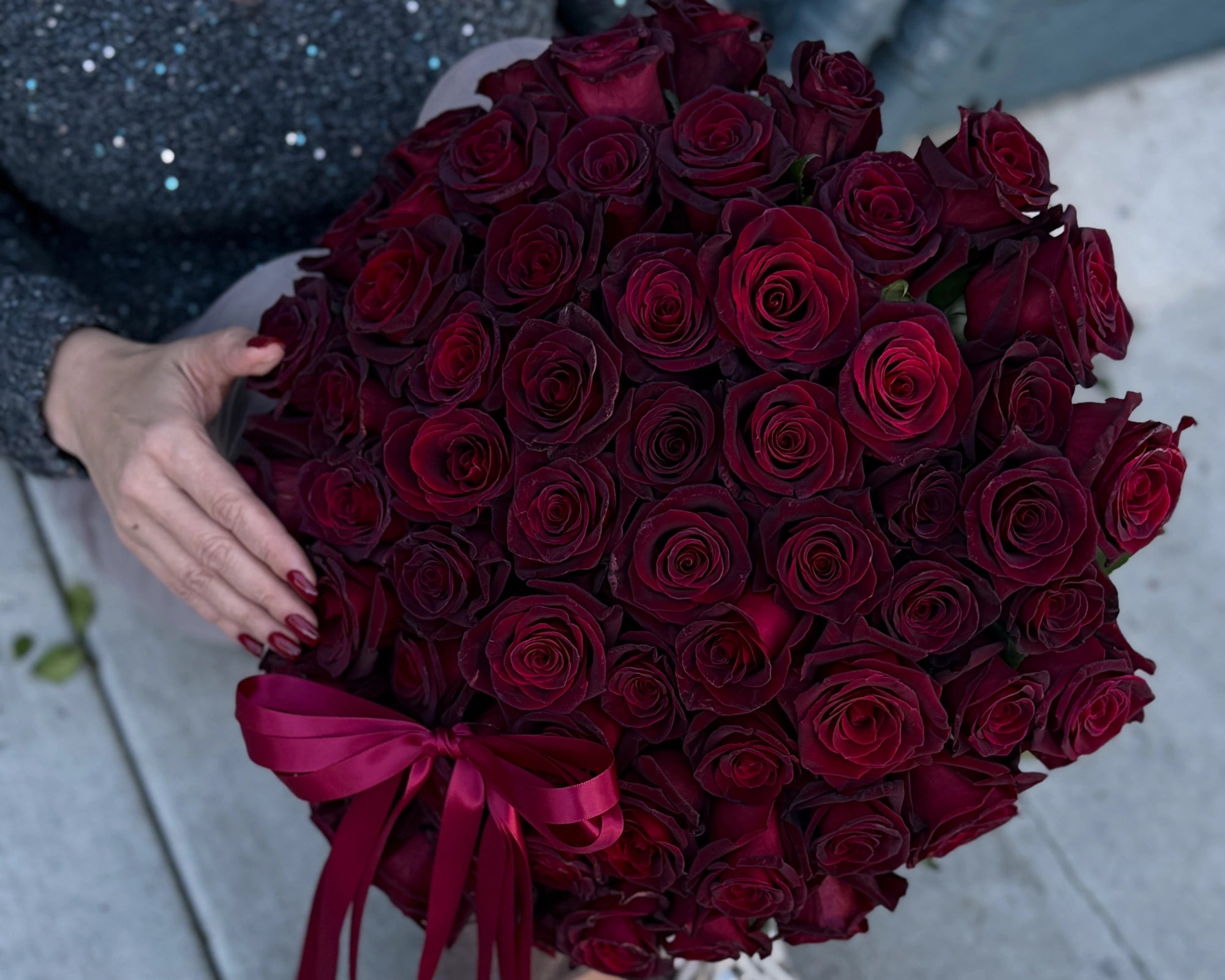 Close-up of Black Baccara roses with velvety dark red petals and satin ribbon, dramatic luxury floral bouquet