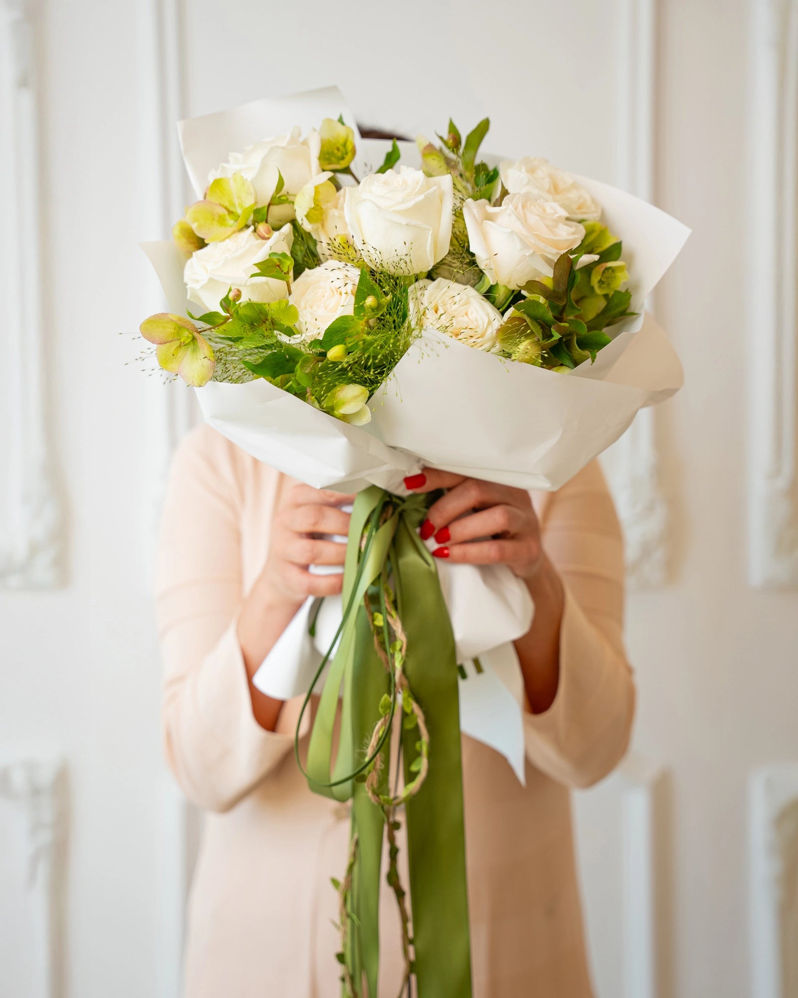 Hand-held ivory garden bouquet featuring cream roses and chartreuse alstroemeria wrapped in white paper with sage ribbon