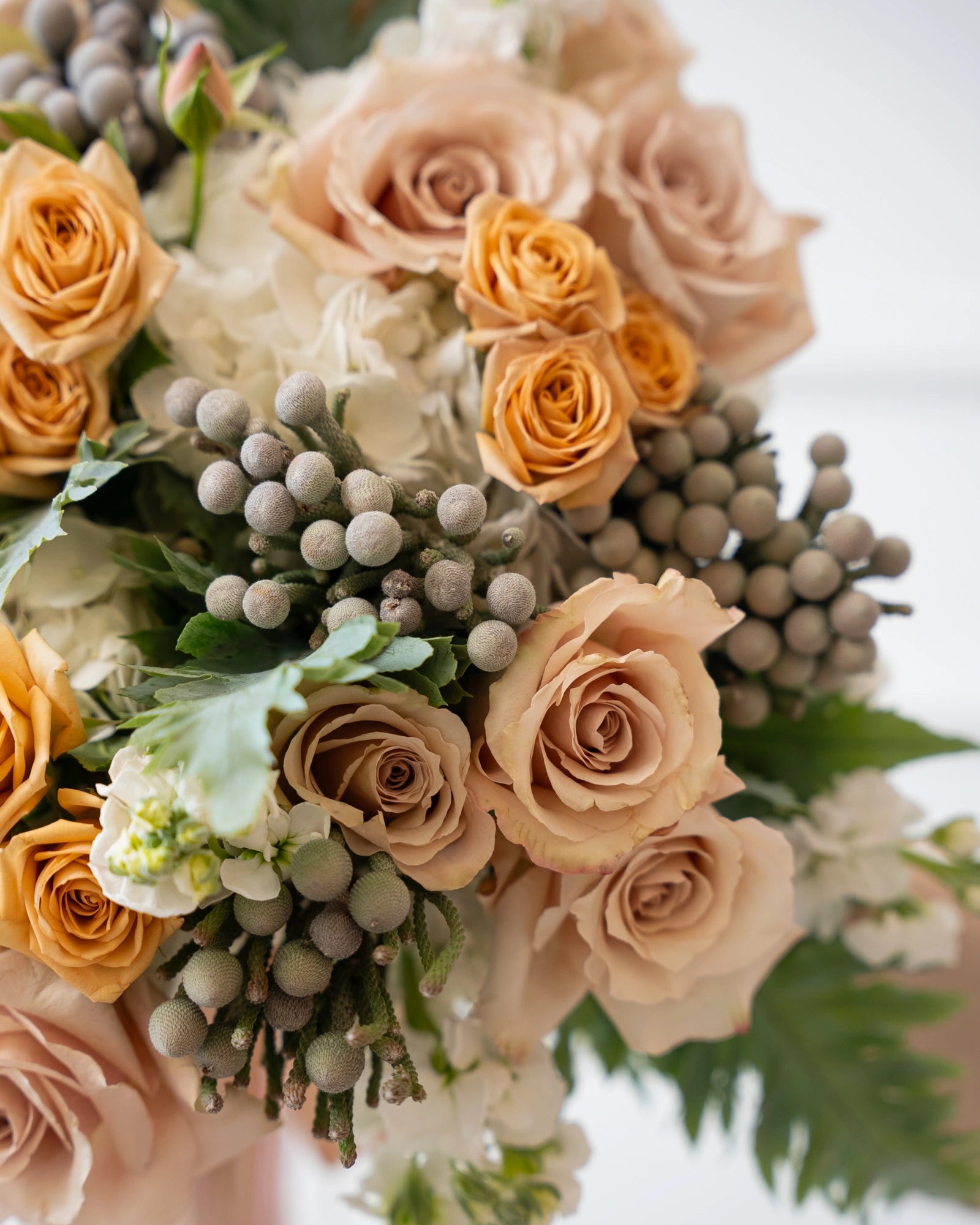 Detail of layered spray roses, garden roses and hydrangea in a round hand-tied design