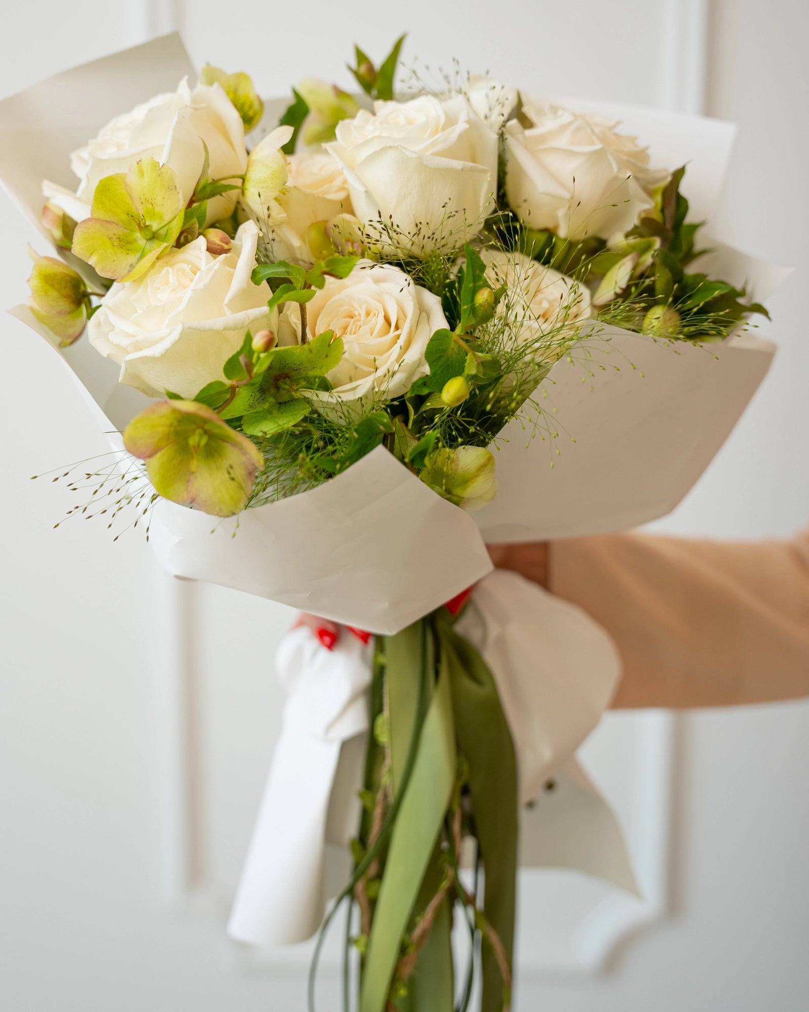 Close-up view of ivory roses paired with green-tinged alstroemeria and delicate filler in elegant round arrangement